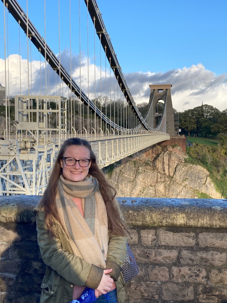 Young woman standing in front of Clifton Suspension Bridge in Bristol, England, UK